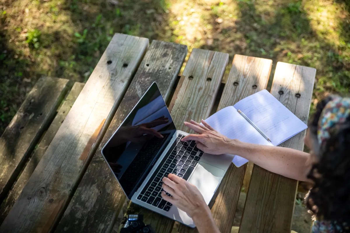 Christine Irabola, consultant SEO qui travaille sur son ordinateur dans un jardin près de Pau